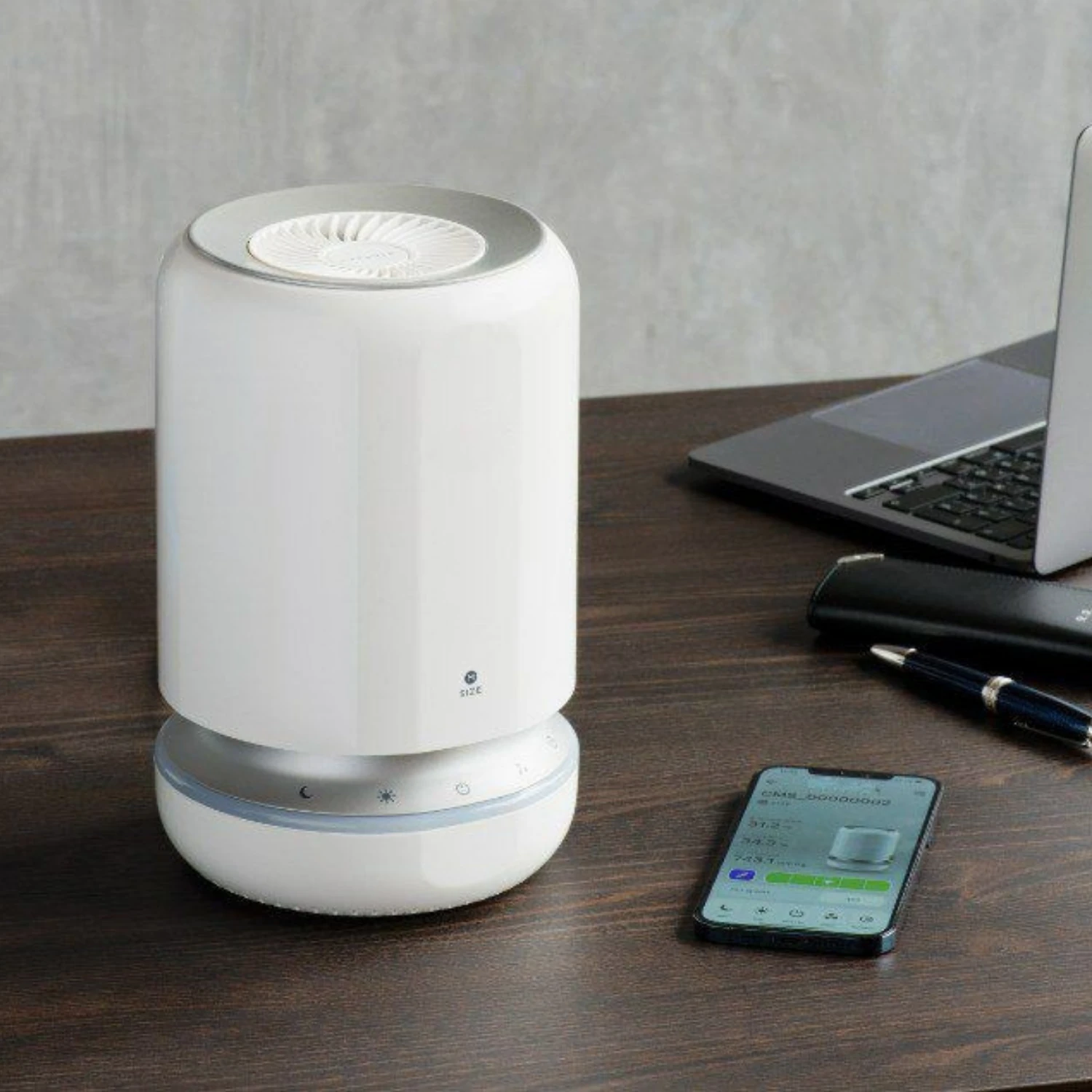 Photocatalytic air purifier on a desk next to a smartphone showing its app